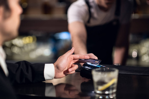 a csapos elfogadja a hitelkártyával történő fizetést a bárban - Fotó, kép