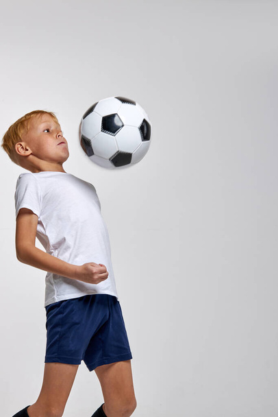 capable sportive boy training alone with soccer ball - Photo, image