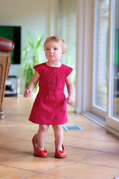 Lovely toddler girl walking indoors in mom's red shoes - Foto, Bild