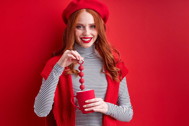 young positive redhead female is having fun with sex toy and cup - Φωτογραφία, εικόνα