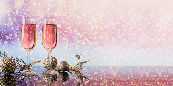 Dos copas de champán rosa y decoración de Navidad o Año Nuevo con bokeh de nieve ligero en el fondo. Cena romántica. Concepto de vacaciones de invierno. - Foto, imagen