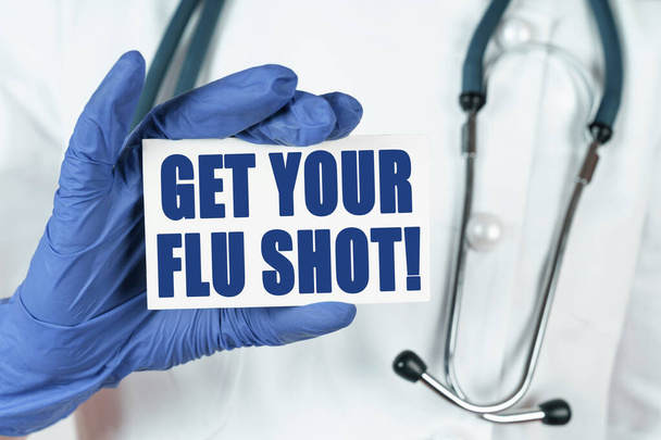 Medicine concept. The doctor holds a business card that says - GET YOUR FLU SHOT - Foto, Bild