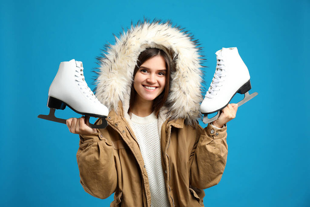 Happy woman with ice skates on light blue background - Zdjęcie, obraz