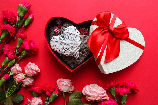 Beautiful greeting card for Valentine's Day. Heart shaped gift box with hearts decorations and flowers on red background. Top view, flat lay. - Foto, Imagem