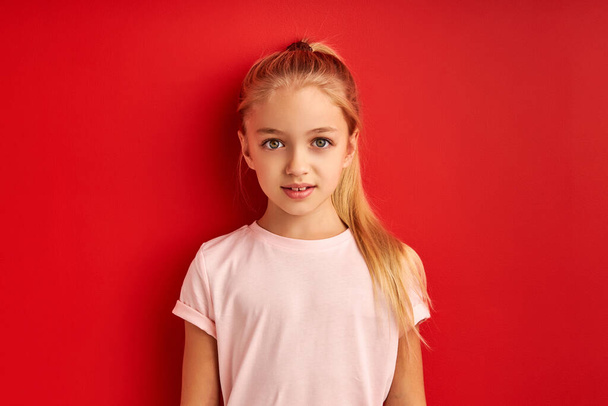 shy confident caucasian child girl isolated over red studio background - Φωτογραφία, εικόνα