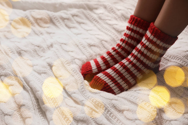 Woman in warm socks on knitted blanket, closeup. Space for text - Foto, imagen