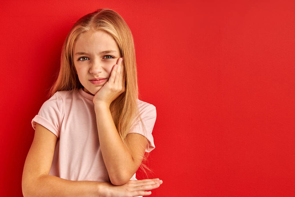 little caucasian girl has toothache, isolated on red background - Φωτογραφία, εικόνα