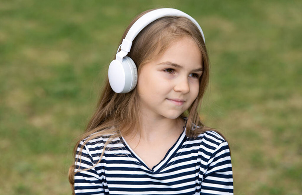 Cute little kid listen to audio language course in headphones outdoors, english - Foto, Imagem