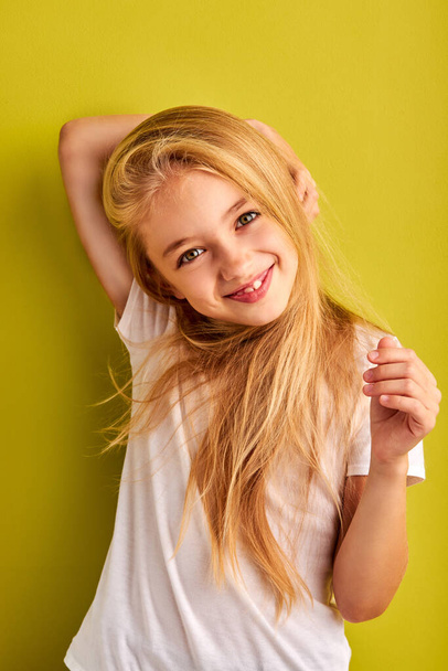 cheerful child girl with long blond hair isolated on green background - Фото, зображення
