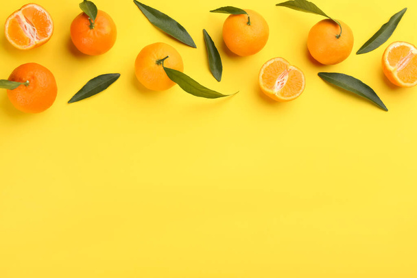 Fresh tangerines with green leaves on yellow background, flat lay. Space for text - Foto, afbeelding