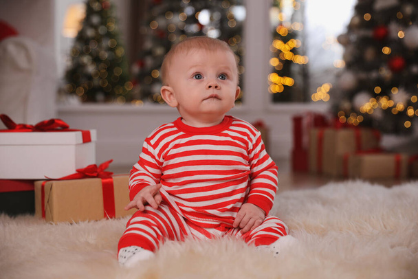 Cute baby in bright Christmas pajamas on floor at home - Foto, afbeelding