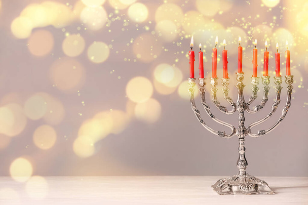 Silver menorah with burning candles on table against light background, space for text. Hanukkah celebration - Foto, immagini