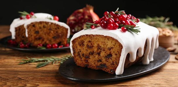 Traditional classic Christmas cake decorated with cranberries, pomegranate seeds and rosemary on wooden table. Banner design  - Photo, image