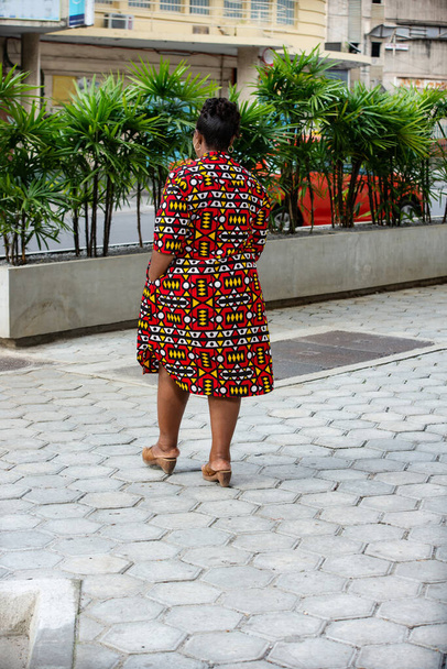 Retrato de vista trasera de una hermosa mujer madura negra con un vestido de taparrabos tradicional caminando por la calle - Foto, imagen