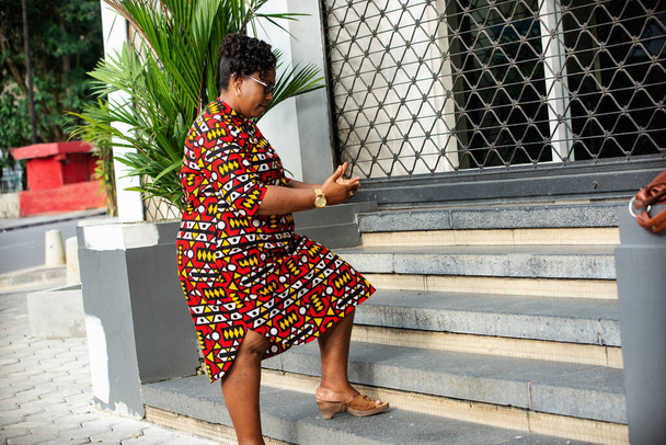kaunis aikuinen nainen, jolla on lasit ja perinteinen lannevaate portaiden portailla - Valokuva, kuva