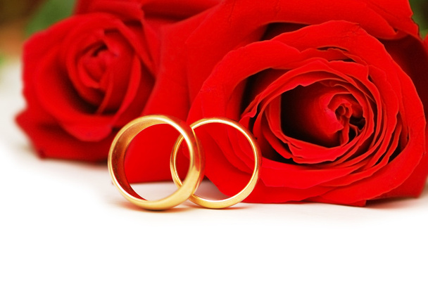 Two wedding rings and red roses isolated on white - Foto, afbeelding