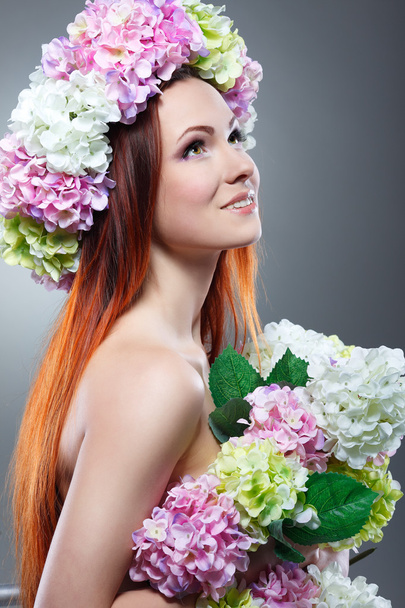 Close-up portrait of beautiful young redheaded girl in a chaplet with  flowers - Photo, Image
