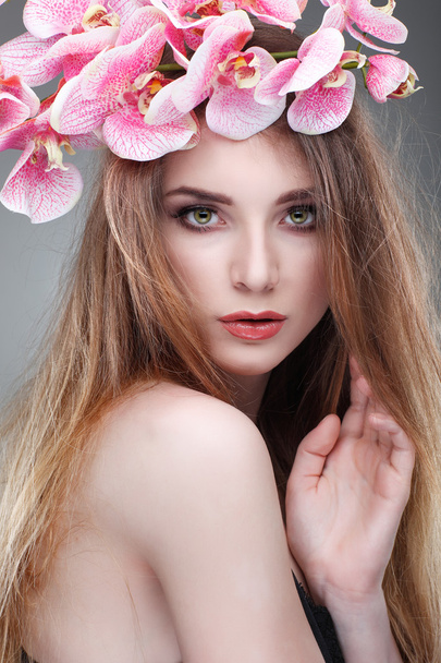 Beautiful  girl, isolated on a light - grey  background with pink orchids in hairs, emotions, cosmetics - Valokuva, kuva