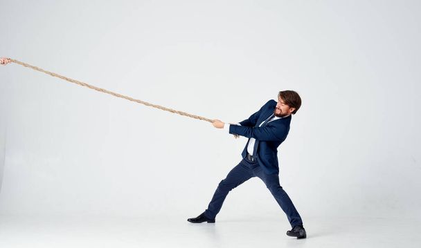 man with rope in hand on light background business finance  - Photo, Image