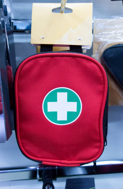 red bag first aid kit with a price tag hangs on the counter in the store. copy space. - Photo, Image