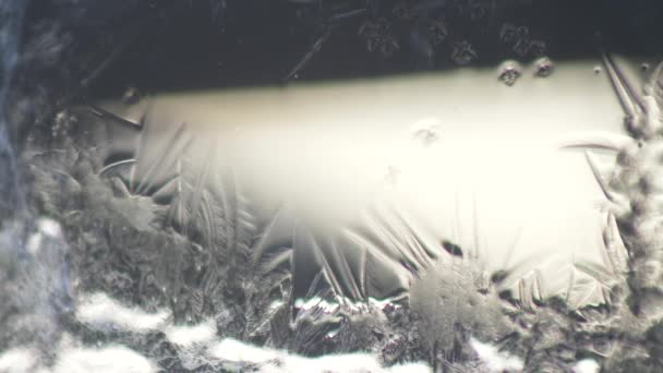 Frostige Muster am Fenster. Frostmuster bedecken den dunklen Hintergrund. 4K - Filmmaterial, Video