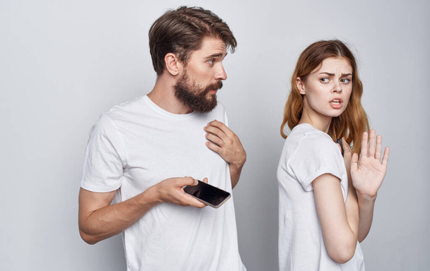 man and woman in white t-shirts with phones in hands romance communication technology - Zdjęcie, obraz