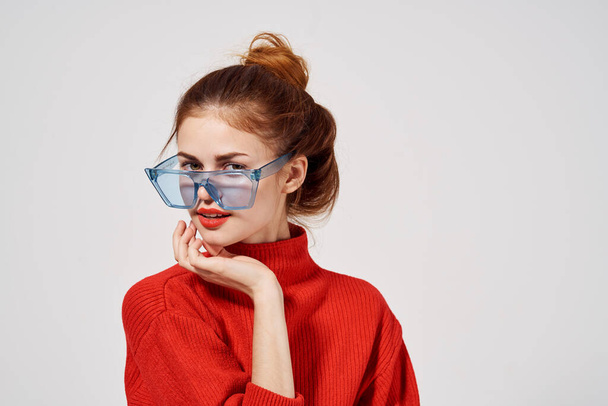 modieuze vrouw in rode trui blauwe bril model lichte achtergrond - Foto, afbeelding