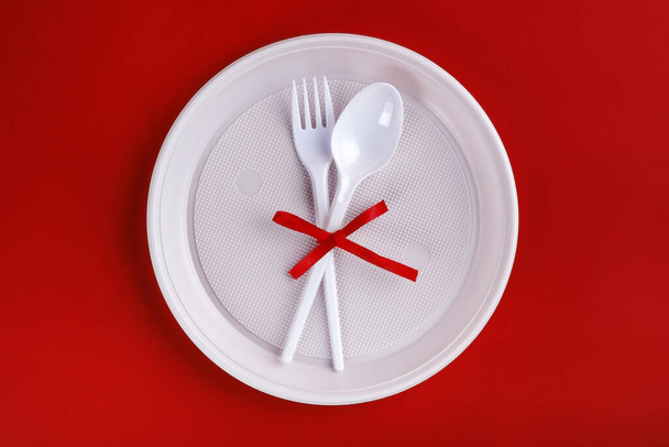 Top view of plastic white disposable fork and spoon tied with red ribbon - Фото, зображення