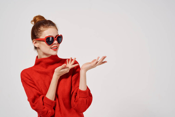 módní žena model v červeném svetru a sluneční brýle gestikuluje rukama - Fotografie, Obrázek