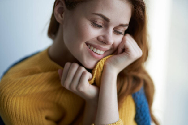 pretty woman in a yellow sweater hiding behind a blanket near the window comfort home interior - 写真・画像