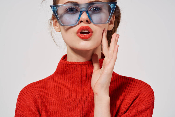 fashionable woman model in a red sweater and blue glasses on a light background emotions cropped view - Photo, Image