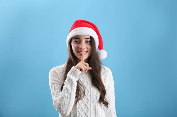 Beautiful woman wearing Santa Claus hat on light blue background - Фото, изображение