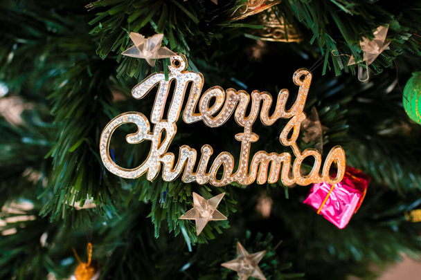 Рождественская елка украшена золотой формулировкой "веселого Рождества", серебряным колоколом и другими украшениями. Отлично подходит для новогодних открыток, подарков, хедлайнеров, партийных плакатов - Фото, изображение
