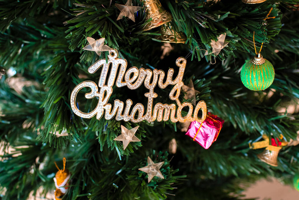 Christmas tree decorated with a gold wording of 'Merry Christmas', silver bell and other ornaments. Great for Christmas and New year cards, banners, headers, party posters - Foto, imagen