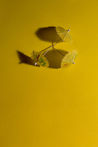 Жовті літні паперові парасольки на жовтому столі і в сильному сонячному світлі з тіні для лиття
 - Фото, зображення