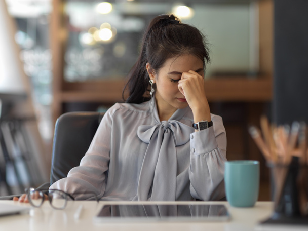 Retrato de una mujer de negocios que se siente estresada mientras trabaja con una tableta digital en la sala de oficina - Foto, Imagen