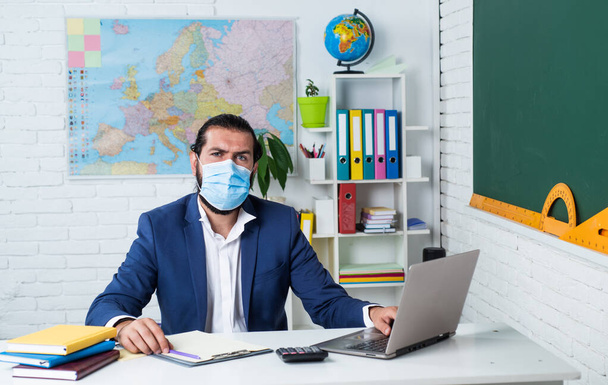 college lecturer on coronavirus pandemic. back to school. nonformal education. mature teacher wear respirator mask. brutal bearded man work in classroom during covid 19. prepare for online exam - Фото, зображення