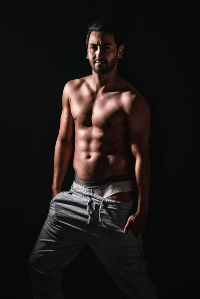 portrait of caucasian strong model with muscles posing isolated on dark background - Fotó, kép