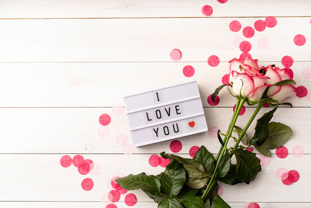 Valentýn. I love you words on a lightbox with pink roses top view flat lay on white background - Fotografie, Obrázek