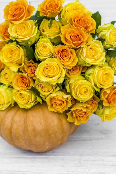 μπουκέτο με κίτρινα τριαντάφυλλα και κολοκύθα σε λευκό ξύλινο πίνακα. Όμορφα κίτρινα τριαντάφυλλα. Φθινόπωρο διακόσμηση - Φωτογραφία, εικόνα