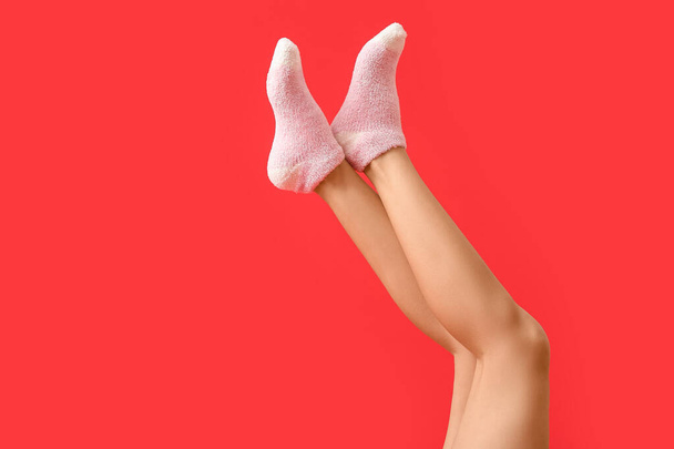 Las piernas de la mujer joven en los calcetines sobre el fondo de color - Foto, Imagen