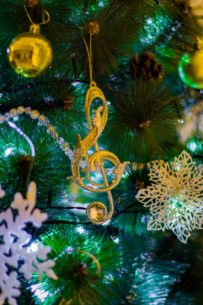 Weihnachtsbaumspielzeug, das am Weihnachtsbaum hängt - Notenschlüssel, Schneeflocken, Kugeln, Tannenzapfen, Perlen, Girlanden. Weihnachtsdekoration. - Foto, Bild