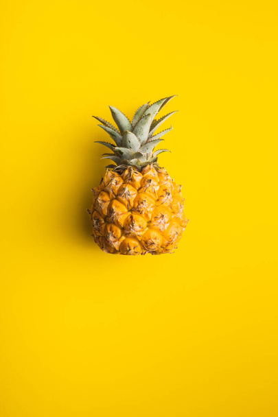 Ripe baby pineapple. Mini pineapple on yellow background. Top view. - 写真・画像