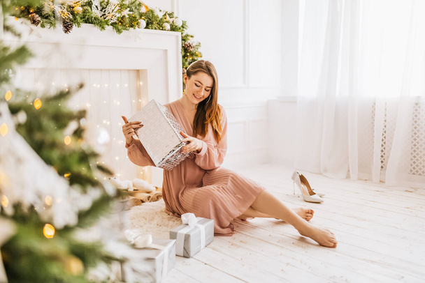 Beautiful cheerful happy young girl with christmas gifts on the background of a new year tree at home - Foto, Bild