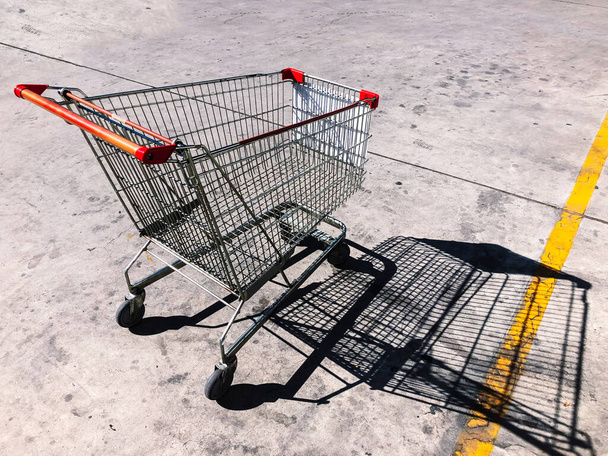Empty Shopping cart in concrete parking lot under strong sunlight. High contrast shadow - Photo, Image