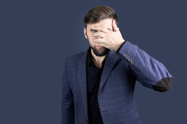 a bearded man in a blue suit covered his eyes with h - Fotoğraf, Görsel