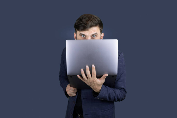 uomo d'affari un uomo con la barba in un abito blu che tiene un computer portatile in una mano - Foto, immagini