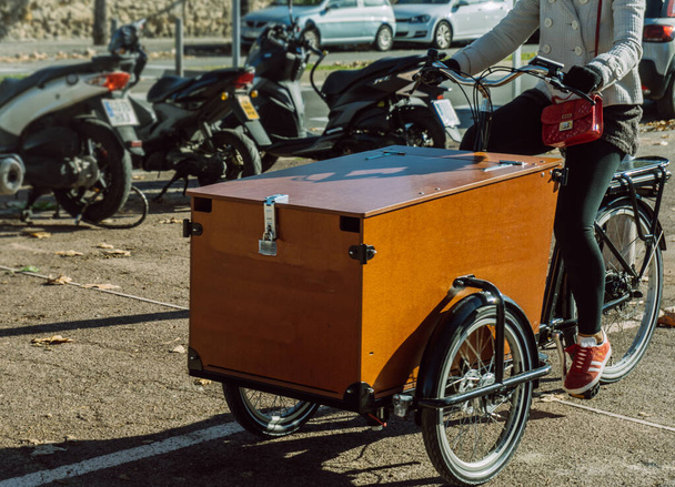 Жінка керує триколісним велосипедом, призначеним для доставки посилок
 - Фото, зображення