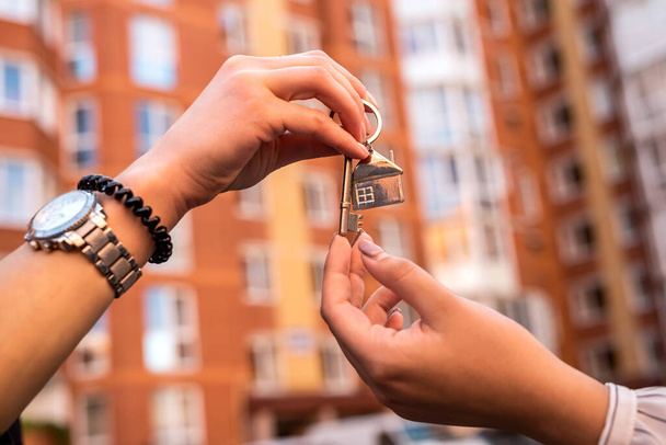agente inmobiliario que entrega la llave de la casa para el nuevo propietario en el fondo de la casa. venta o alquiler de casa - Foto, imagen