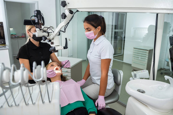 Une dentiste vérifie les dents des patientes au microscope et aux instruments de la clinique moderne. Soins de santé - Photo, image